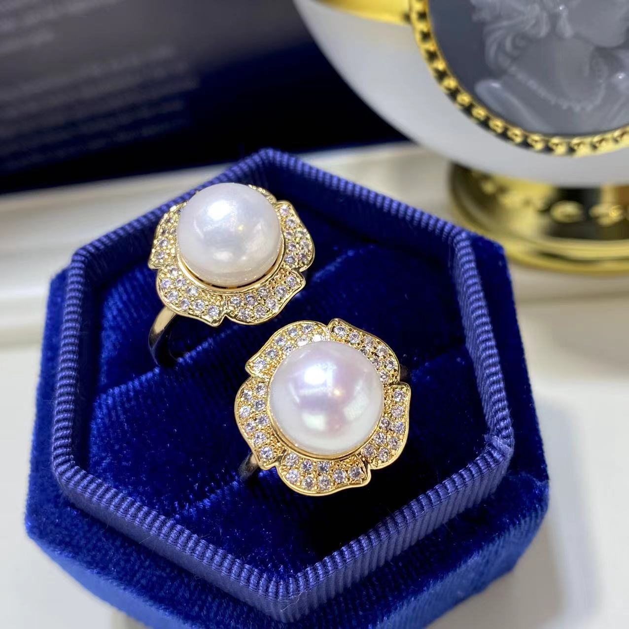 Luxury lavender jewelry set featuring pearl and gold rings with sparkling crystals in blue velvet box