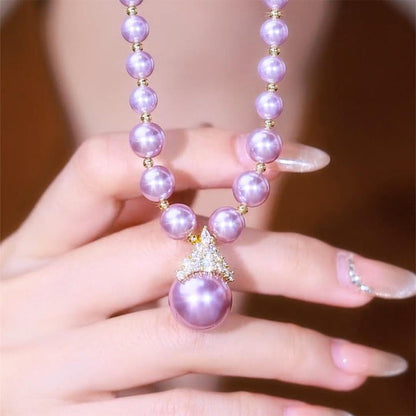 Luxury pearl jewelry set with lavender pearls and crystal pendant held over a hand with manicured nails