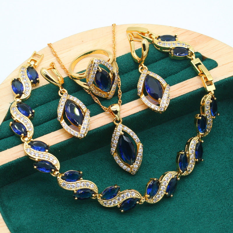 Luxury peridot jewelry set featuring gold-tone necklace, earrings, bracelet, and ring with deep blue stones and clear crystals