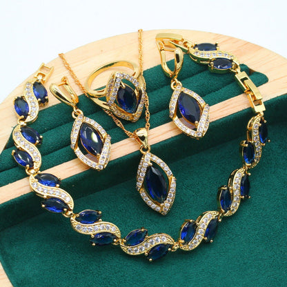 Luxury peridot jewelry set featuring gold-tone necklace, earrings, bracelet, and ring with deep blue stones and clear crystals