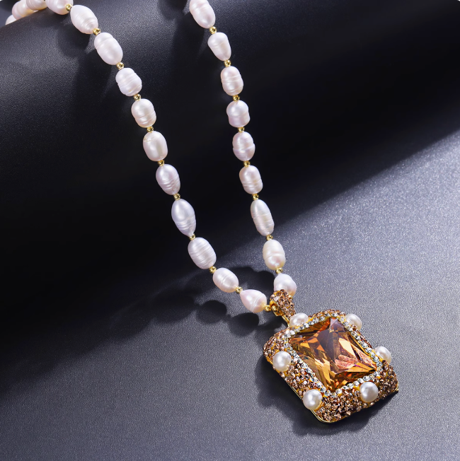 Elegant pearl jewelry set featuring white pearls and a gold pendant with amber gemstone