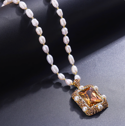 Elegant pearl jewelry set featuring white pearls and a gold pendant with amber gemstone